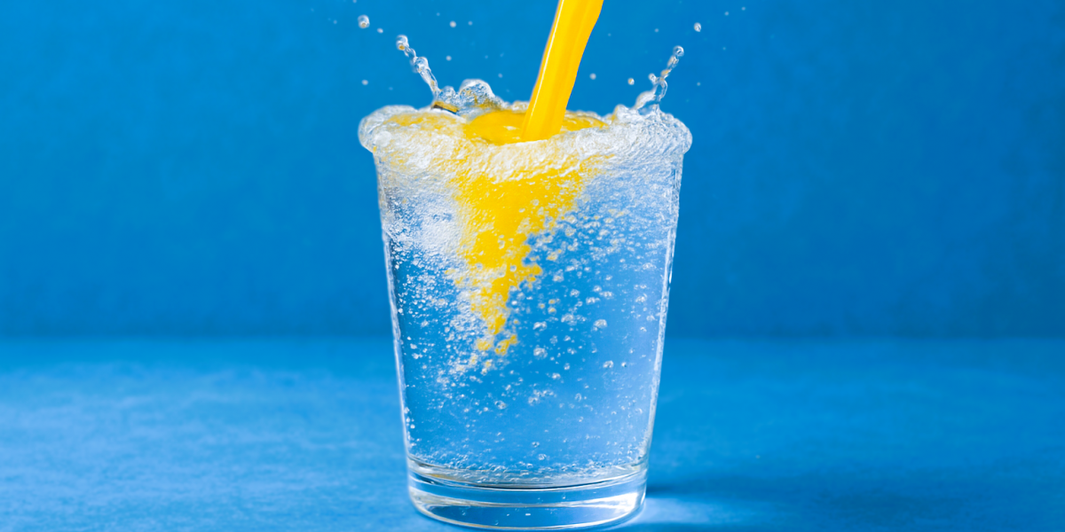 Wasserglas. Orangensaft wird dazu eingeschüttet. 